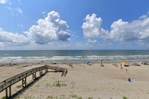A beach with a wooden pier, sandy shore, and ocean waves.