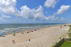 A beach with umbrellas, tents, and a boardwalk.