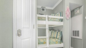 Una habitación con literas, una puerta con cerradura de seguridad y una rejilla en la pared.