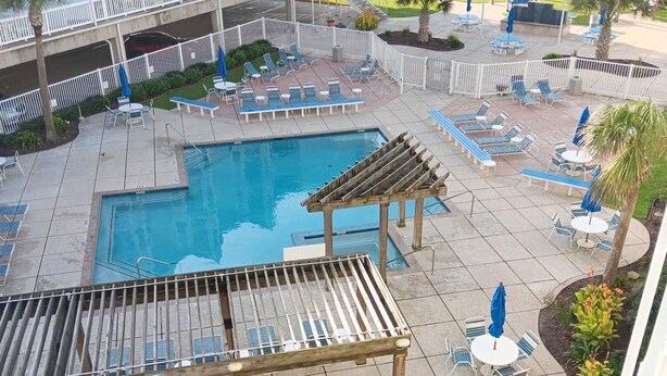 A rooftop pool area with lounge chairs, a pergola, and a view of the beach. - Seascape 1318 in Galveston (Galveston)