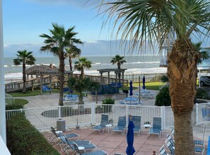 A beachside resort with lounge chairs, palm trees, and a view of the ocean. - Seascape 2107 in Galveston (Galveston)