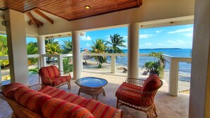 Un espace extérieur aménagé, abrité et doté de mobilier en osier, offrant une vue sur la plage.