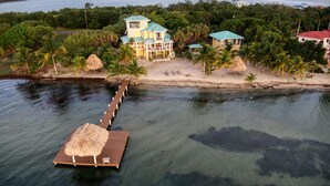Un complexe hôtelier tropical doté d’un quai menant à une plateforme en bois surmontée d’un parasol en chaume.
