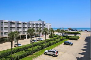 Situated near the coast, this hotel features a central tower with a distinctive roof and a well-manicured parking area surrounded by palm trees.