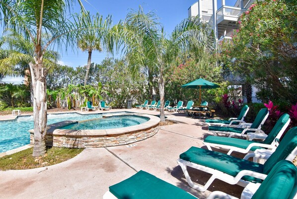 Relax by the pool surrounded by lush tropical plants and lounge chairs.
