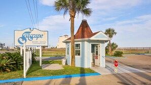 Un petit bâtiment bleu avec un toit rouge, un panneau de signalisation et une enseigne indiquant « Seascape Resort Rental Condominiums ».