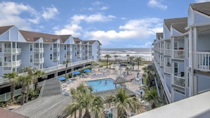 Un hôtel situé en bord de mer, composé de plusieurs bâtiments à étages, doté d’une piscine et offrant une vue sur l’océan.