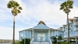 A guest registration building with a front porch, steps, and palm trees. - Seascape 2201 in Galveston (Galveston)