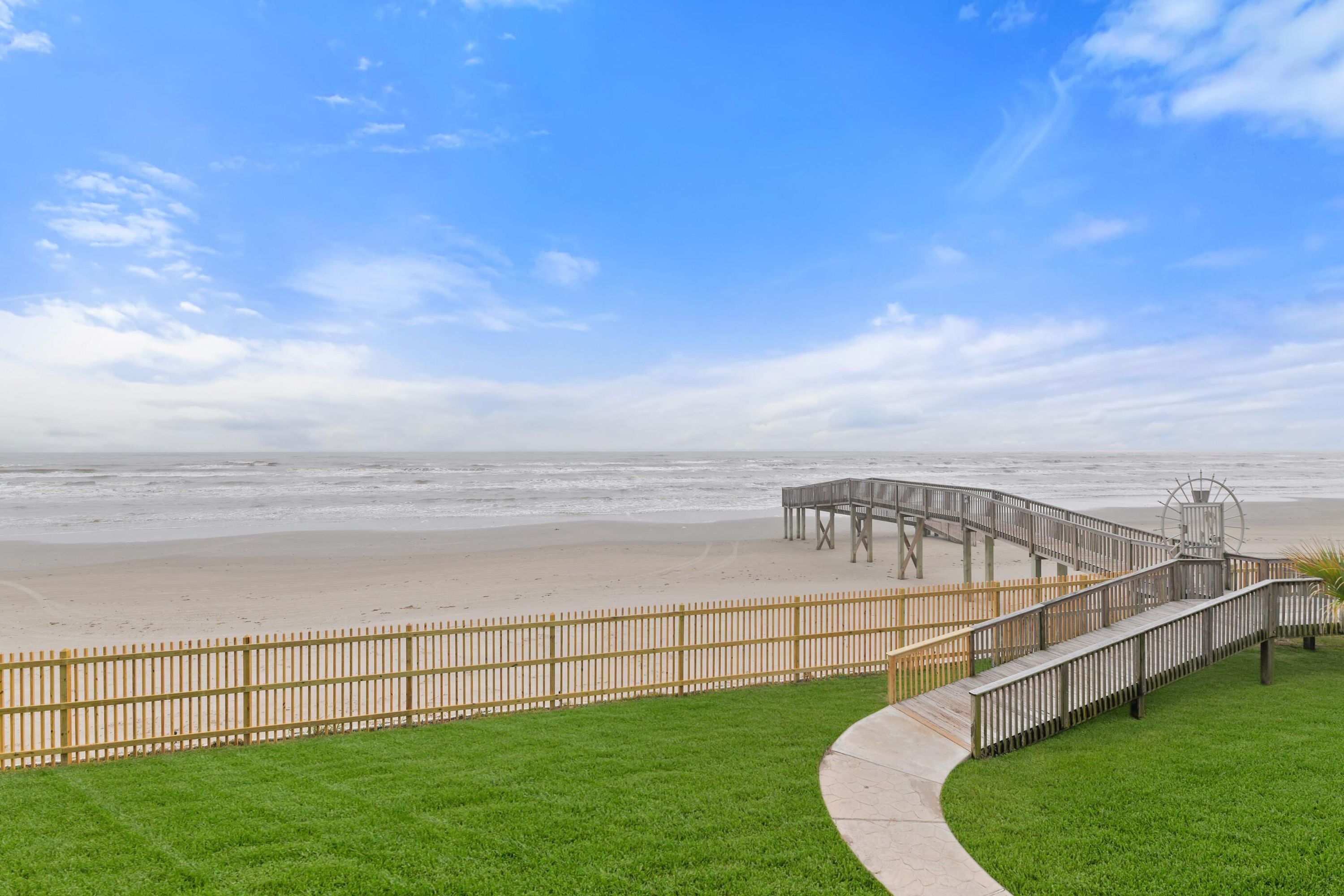 Ein Strand mit einer Holzpromenade, die zu einem Steg führt.