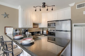 Enjoy cooking in this well-equipped kitchen with a central island, stainless steel appliances, and white cabinetry.