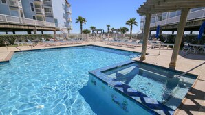 Un espace piscine avec une eau d’un bleu limpide, des chaises longues et une structure en forme de pergola.