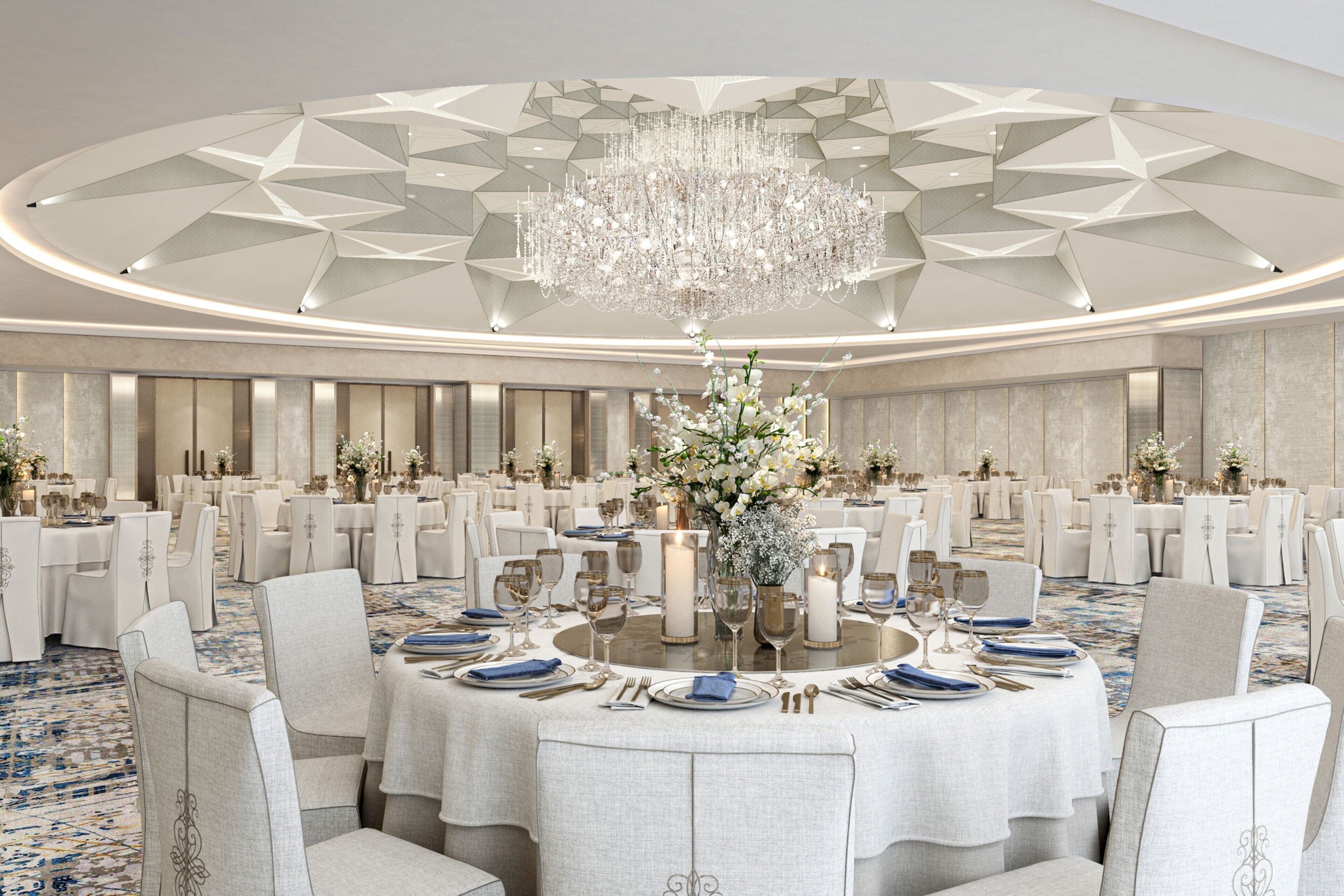 A banquet hall with round tables, white chairs, and a large chandelier.