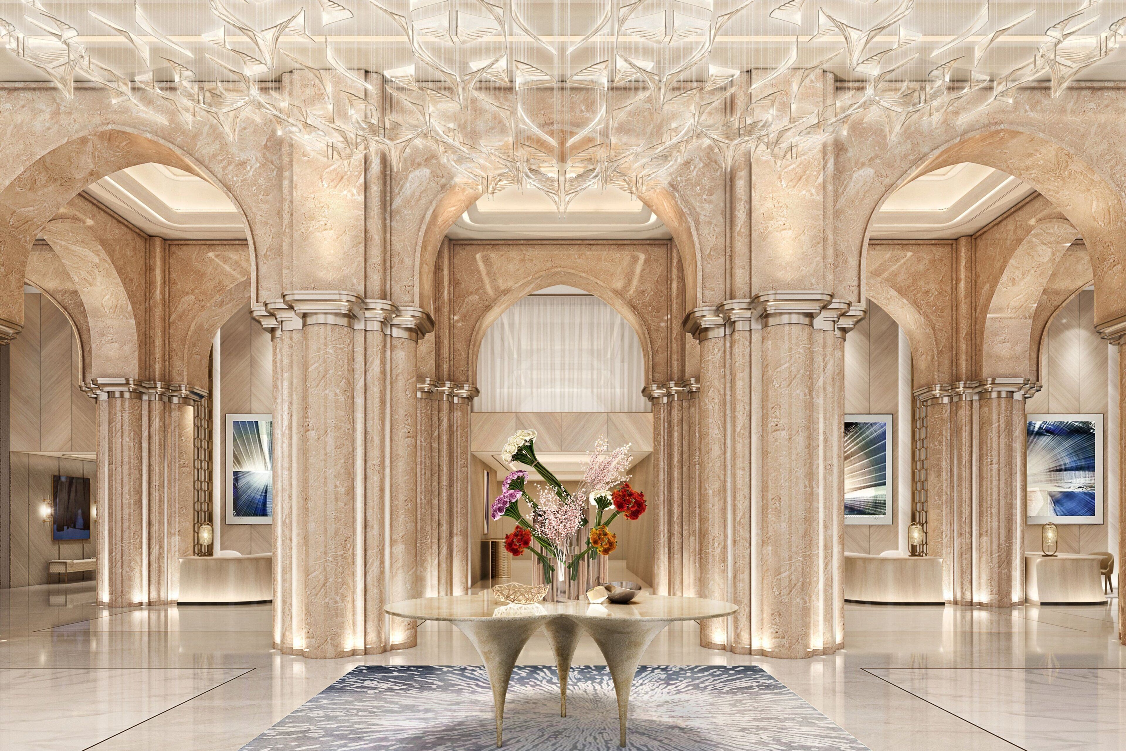 A luxurious lobby with marble columns, a central table with a vase of flowers, and modern artwork on the walls.