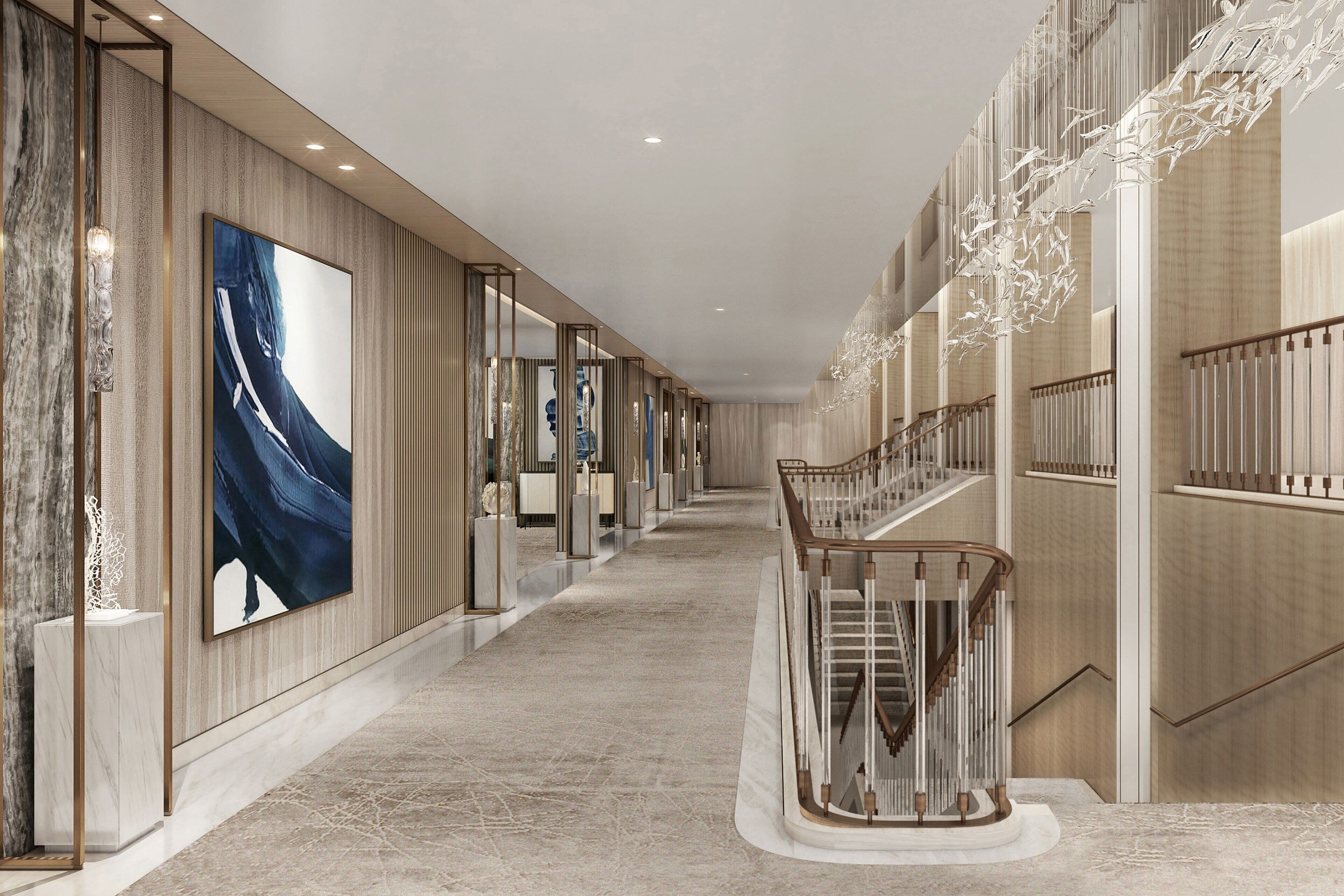 A modern hotel corridor with a marble floor, a staircase with a wooden railing, and a large abstract painting on the wall.