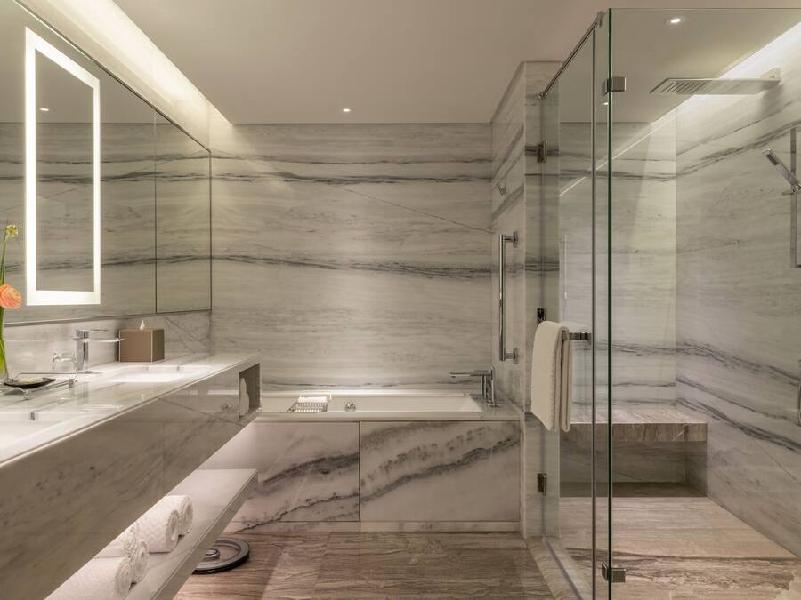 A modern bathroom with a glass-enclosed shower, a marble vanity, and a large mirror.