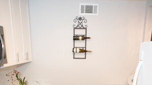 A compact kitchen with white cabinets, a marble countertop, a built-in oven, a sink, and a decorative wall piece. - Downtown Waterfront Condo (Pensacola)