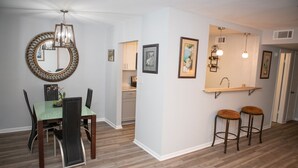 A modern kitchen with a built-in island, bar stools, and pendant lighting. - Downtown Waterfront Condo (Pensacola)