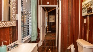 A bathroom with a wooden floor, a white sink, and a toilet. - Yeti Cabin (Benton)
