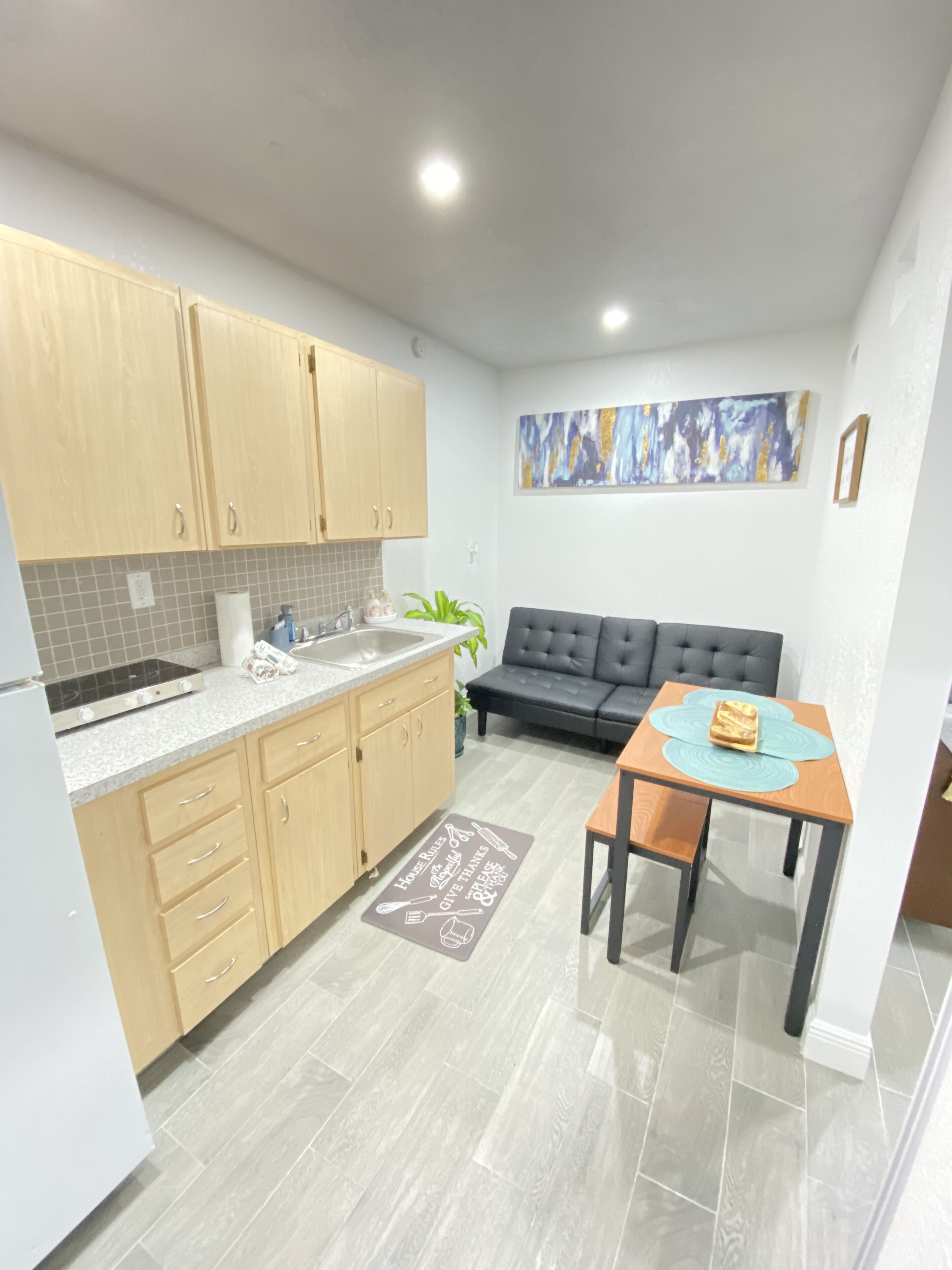 A compact kitchen with wooden cabinets, a built-in stove, and a grey tiled backsplash.