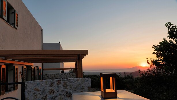 Una terraza con un muro de piedra, muebles de madera y un farol.