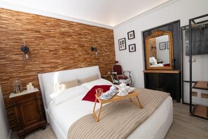 Ein Schlafzimmer mit einer Wand in Holzoptik, einem Bett mit einem Tablett mit Frühstücksartikeln, einem Nachttisch, einem Spiegel und einem Kleiderschrank.