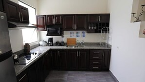 A compact kitchen with dark cabinets, a microwave, a stove, and a sink. - Special Discount!! The Artist Condo in Barrio Dent (San Pedro)