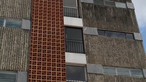 A multi-story building with a distinctive red grid facade and a mix of vertical and horizontal window patterns. - Special Discount!! The Artist Condo in Barrio Dent (San Pedro)