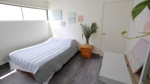 A bedroom with a bed, a nightstand, a potted plant, and artwork on the wall. - Special Discount!! The Artist Condo in Barrio Dent (San Pedro)
