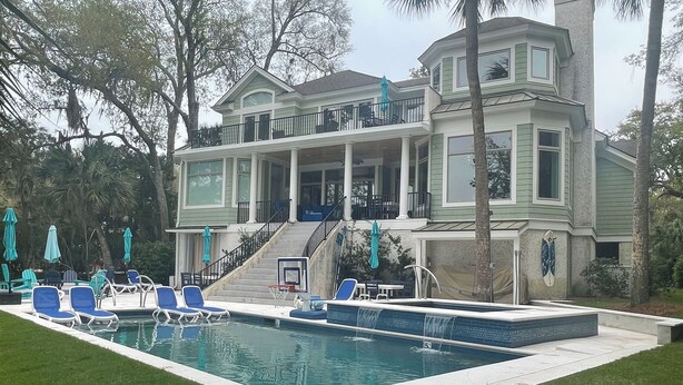 A large house with a swimming pool, a covered patio, and a staircase leading to a balcony. - Island Escape! Pool, Elevator, Pinball, Foosball, Arcade, Nursery,Infrared Sauna (Hilton Head Island)