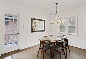 A dining area with a round table, six chairs, and a chandelier.