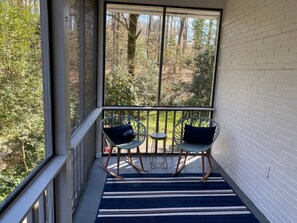 A balcony with two rocking chairs and a small table, overlooking a wooded area. - Mid Century Modern Morningside VA Highland Emory (Atlanta)