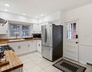 A modern kitchen with white cabinetry, a stainless steel refrigerator, a microwave, and a gas stove. - Mid Century Modern Morningside VA Highland Emory (Atlanta)