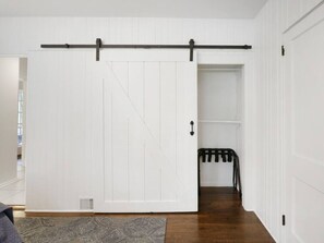 Une pièce dotée d’une porte coulissante blanche de style grange, d’un plancher en bois foncé et d’un tapis à motifs gris.