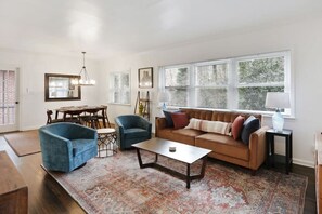 A living room with a brown sofa, two blue armchairs, a coffee table, and a patterned rug.