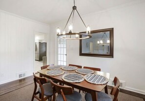 A dining room with a wooden table, six chairs, and a chandelier.