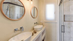 A modern bathroom with two sinks, a shower, and two mirrors.