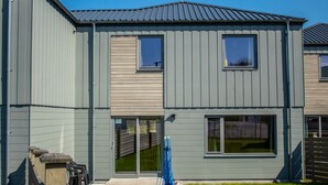A two-story building with a grey exterior, large windows, and a visible garage door. - Alpine View - a cosy Aviemore family home (Aviemore)