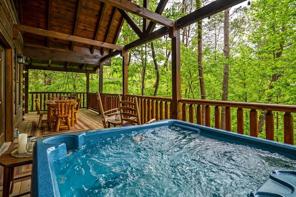 Un bain à remous sur une terrasse en bois, avec vue sur une forêt.