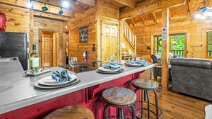Ein Holzblockhaus-Interieur mit Barbereich, Holzwänden und einer Treppe.