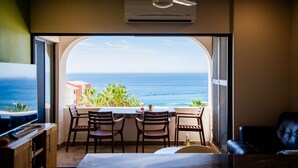A room with a view of the ocean, a ceiling fan, and a table with chairs. - COZY, OCEAN VIEW CONDO WITH PRIVATE BEACH ACCESS (CABO SAN LUCAS)