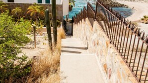 A coastal hotel with a staircase leading to a balcony overlooking the ocean. - COZY, OCEAN VIEW CONDO WITH PRIVATE BEACH ACCESS (CABO SAN LUCAS)