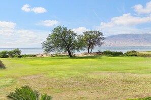 Campo de golfe com vista para o mar e montanhas ao fundo.