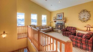 A spacious living room with a fireplace, a clock on the wall, and a staircase leading to an upper level. - Cozy 2BD/2BA Mountain View Condo, near skiing, Sleeps 4+ (Park City)