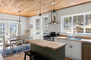 Una cocina moderna con armarios de madera, una isla grande y vistas al bosque.
