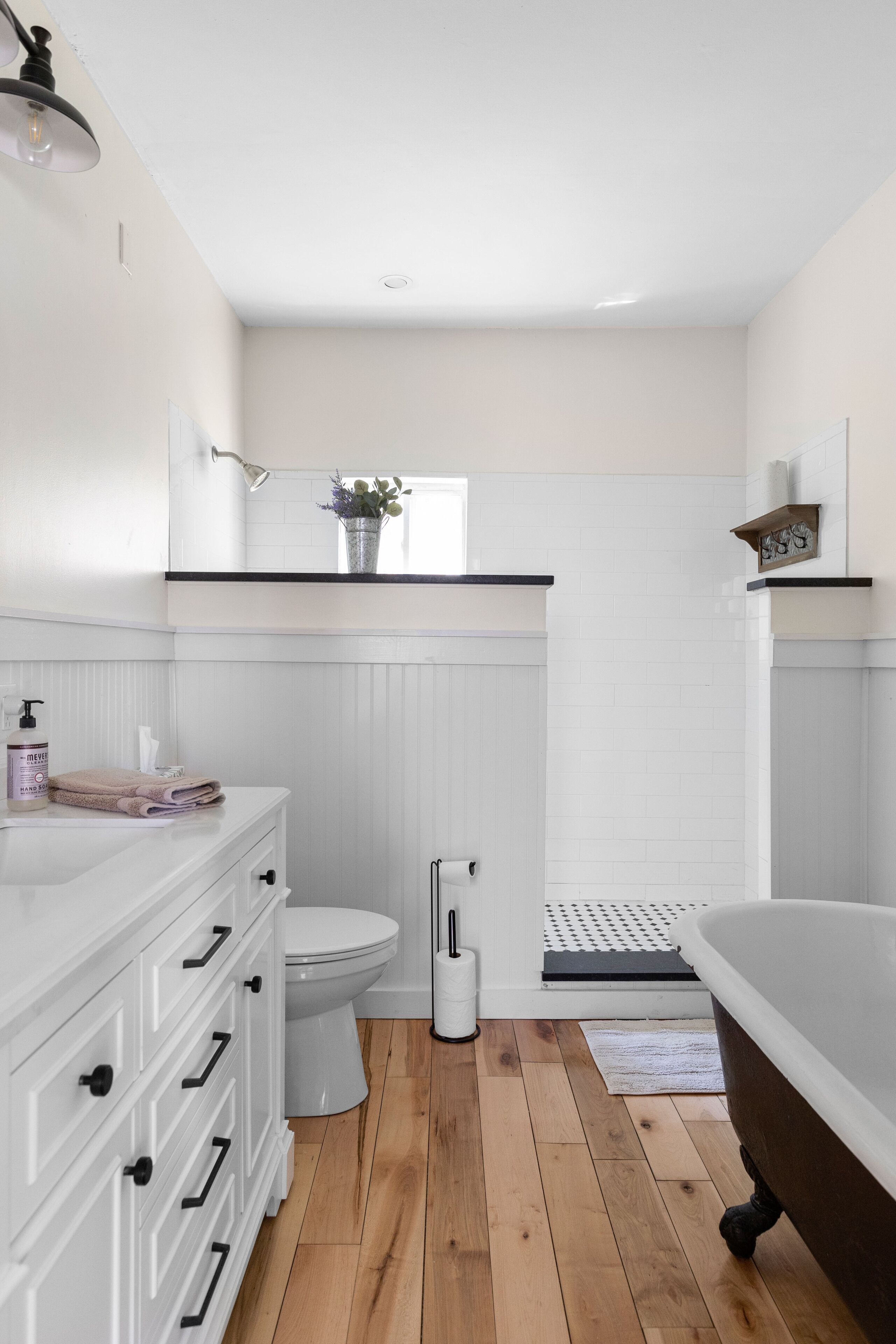 A modern bathroom with a white vanity, a toilet, a bathtub, and a shower area.