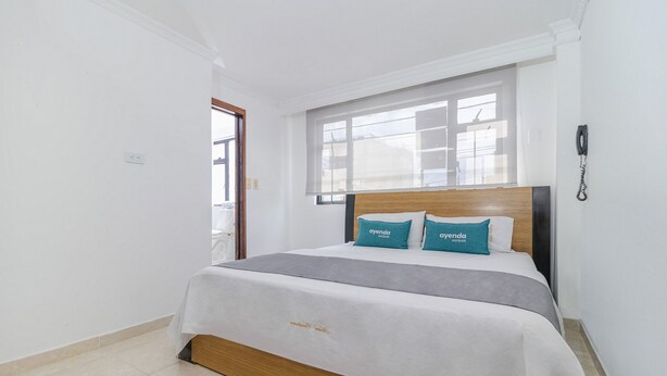 Een hotelkamer met een bed, een raam en een telefoon aan de muur.