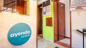 Een hotelingang met een bordje voor 'ayenda HOTELS' en een receptiebalie.