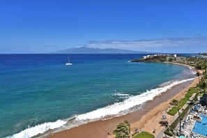A beach resort with a swimming pool, a sandy beach, and a view of the ocean.