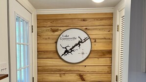A hallway with wooden paneling, a compass-themed wall decoration, and a white door with a window. - Canvasback Cabin - 2bd/2ba (Scottsboro)