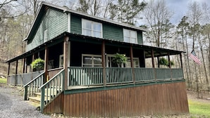 A two-story cabin with a porch and a flag. - Canvasback Cabin - 2bd/2ba (Scottsboro)